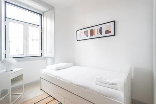 ein weißes Schlafzimmer mit einem Bett und einem Fenster in der Unterkunft FLH Lx Factory Charming Place in Lissabon