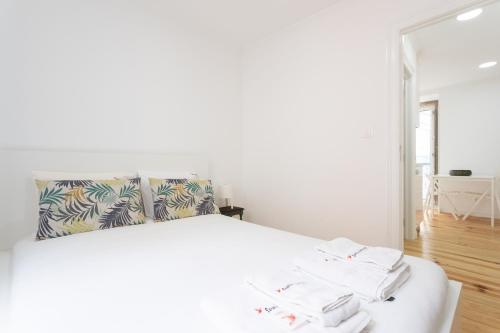 um quarto com uma cama branca e toalhas em FLH Mouraria Charming Flat II em Lisboa