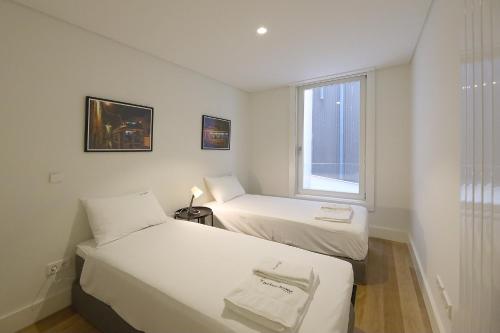 - 2 lits dans une petite chambre avec fenêtre dans l'établissement FLH Porto Spacious Duplex, à Porto
