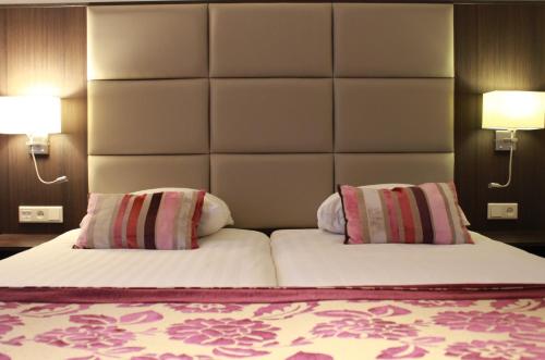 a bedroom with a large bed with two pillows at Hotel Middelburg in Middelburg