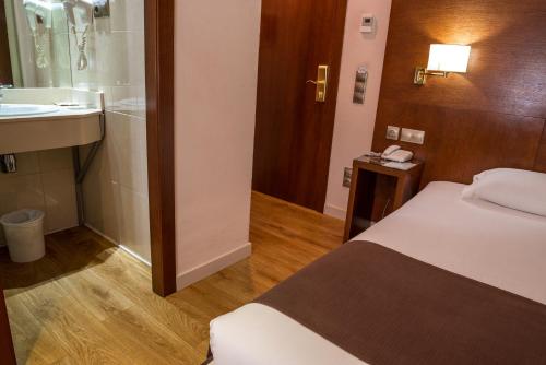 een slaapkamer met een bed en een badkamer met een wastafel bij Ramon Berenguer IV in Lleida