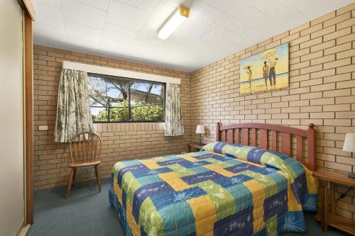 a bedroom with a bed and a chair and a window at Angabunga in Point Lookout