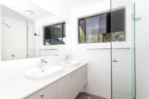 a bathroom with two sinks and a glass shower at McLeod in Point Lookout