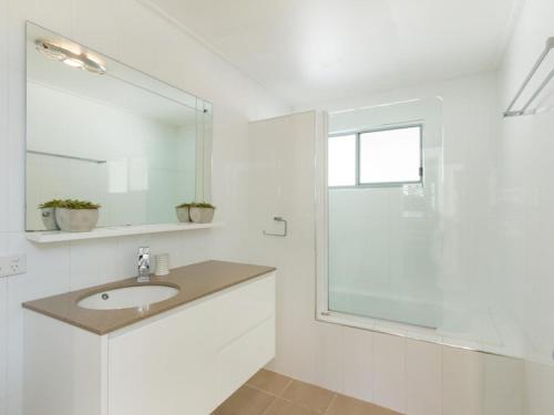 a white bathroom with a sink and a shower at At Melaleuca 3 in Point Lookout
