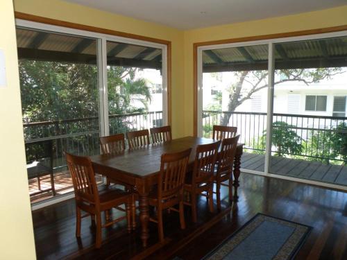 una sala da pranzo con tavolo, sedie e finestre di 11 Bambara Street a Point Lookout