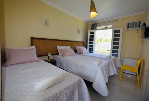1 dormitorio con 2 camas y silla amarilla en Pousada Aruana Praia, en Aracaju