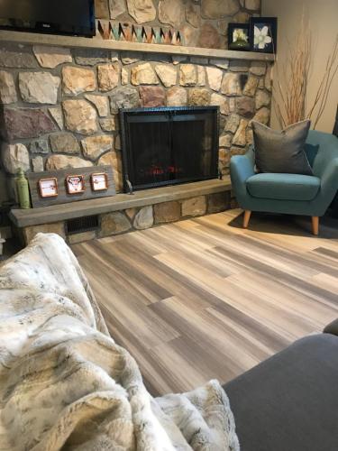 ein Wohnzimmer mit einem Steinkamin und einem blauen Stuhl in der Unterkunft Four Cedars Accommodation in Jasper