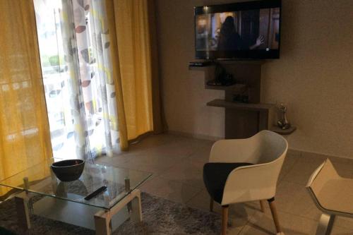 a living room with a glass table and a chair at AU BONHEUR DE PINPIN in Les Abymes
