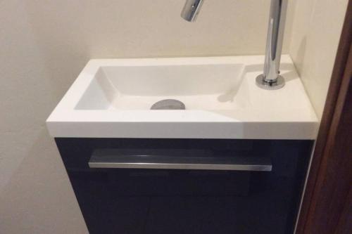 a white sink in a bathroom with aaucet at AU BONHEUR DE PINPIN in Les Abymes