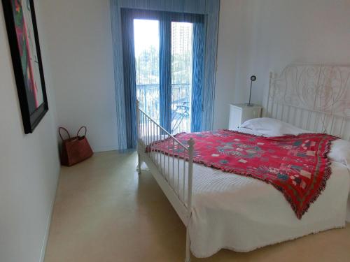 una camera da letto con un letto con una coperta rossa e una finestra di Residence Tintoretto a Lignano Sabbiadoro