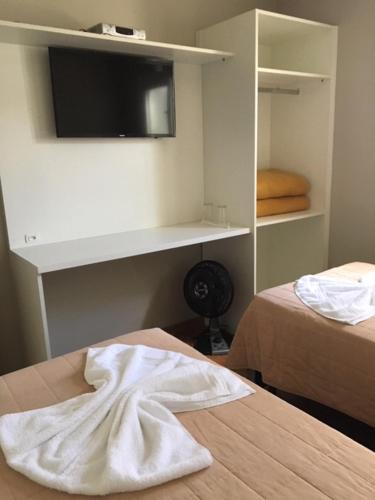 a bedroom with a bed and a tv on a wall at Pousada dos Pinheirais in Nova Prata