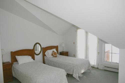 a white room with two beds and a mirror at Maple Hill Farm Bed & Breakfast in New London