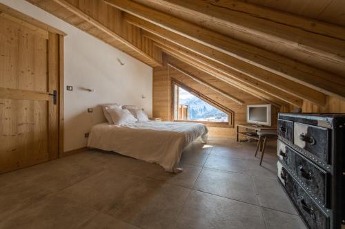 1 dormitorio con cama y ventana en ODYSSEE B301 Duplex mansarde sur les pistes, vue panoramique en La Toussuire