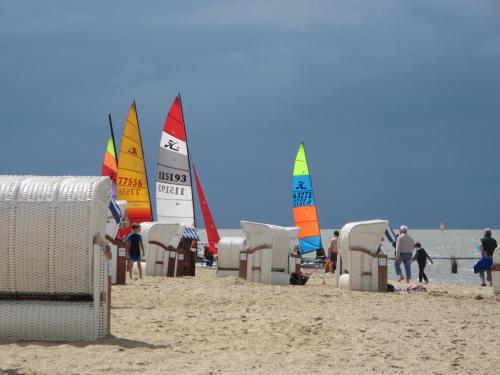 a group of sail boats on a beach with people at Beachhotel Cuxhaven in Cuxhaven