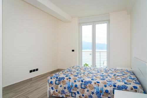 una camera bianca con un letto e una grande finestra di Appartamento Fronte Mare a Portoferraio