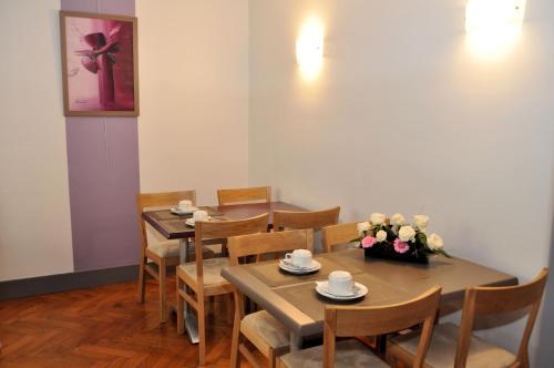 una sala da pranzo con tavoli, sedie e un vaso di fiori di Hotel Lux a Grenoble