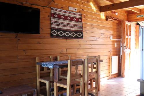 a dining room with a table and chairs and a flat screen tv at Los Condores Bariloche in San Carlos de Bariloche