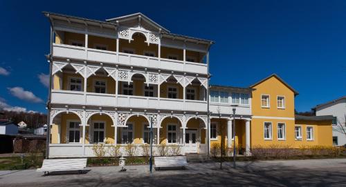 ein gelbes und weißes Gebäude mit einer Bank davor in der Unterkunft Haus Sonne in Ostseebad Sellin
