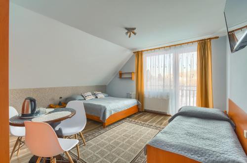 a bedroom with two beds and a table and chairs at Willa U Artura in Tylicz