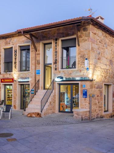 a building with a dog laying in front of it at O balcón da ribeira in Parada del Sil