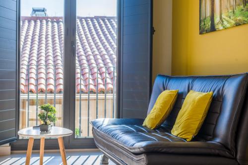 a leather couch with yellow pillows in front of a window at O balcón da ribeira in Parada del Sil