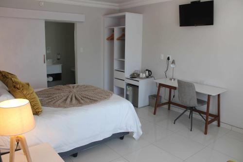 Schlafzimmer mit einem Bett, einem Schreibtisch und einem Tisch in der Unterkunft Prisatt Boutique Hotel in Onverwacht