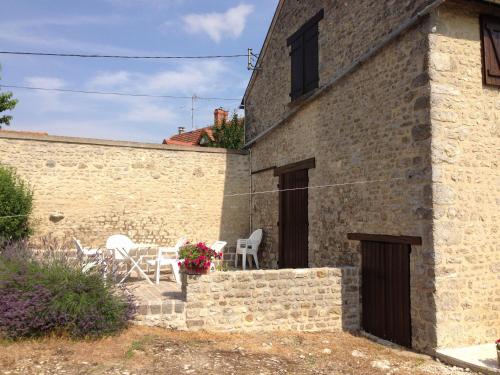 a stone house with a table and chairs outside at Appart dans fermette in Audeville