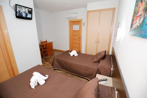 two beds in a room with towels on the beds at Hostal Conde David in Salamanca