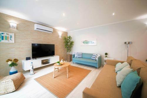 a living room with a couch and a tv at Casa da Baía by Estilo Lusitano, a 150 metros da praia in Porto Covo