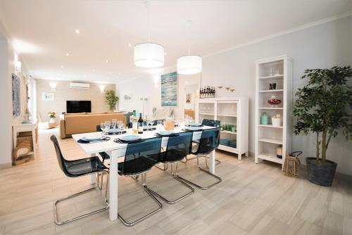 a dining room and living room with a table and chairs at Casa da Baía by Estilo Lusitano, a 150 metros da praia in Porto Covo