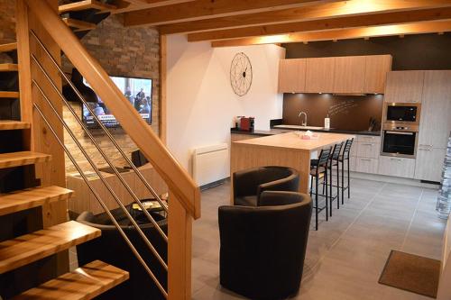 une cuisine avec un comptoir et un bar avec des tabourets dans l'établissement Chalet Les Camélias SPA, à Gérardmer