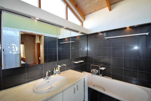 een badkamer met een wastafel, een bad en een spiegel bij Villa Winglo in Rand Rifles