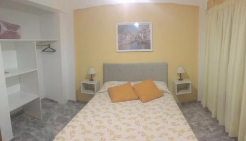 una camera da letto con un letto con due cuscini arancioni sopra di EDIFICIO COSTANERA a Las Toninas