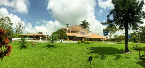 a house in a field of grass with a house at Cotinga Hotel Spa in Pereira