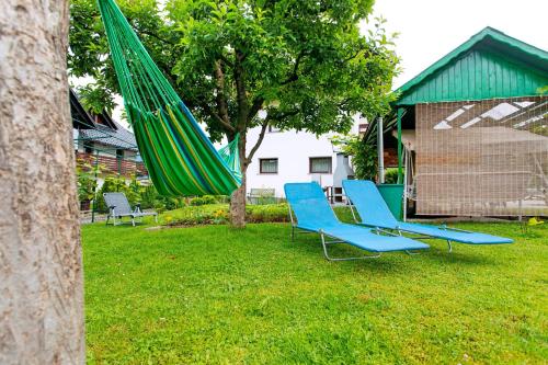 two blue chairs and a green umbrella in a yard at Apartments Green Paradise in Bohinj