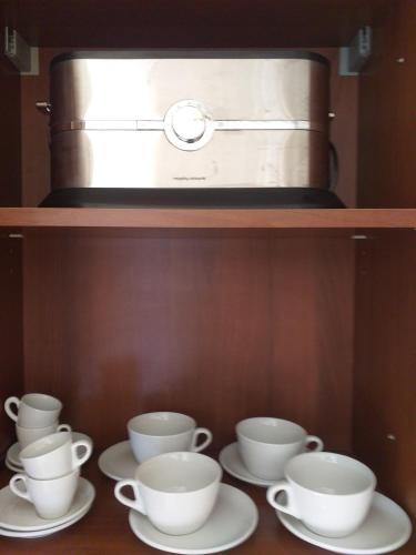 a shelf with three cups and saucers in a microwave at Kalypso View Apartments in Letimbou