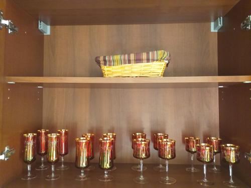 a row of gold and red wine glasses on a shelf at Kalypso View Apartments in Letimbou