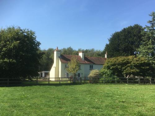 a white house with a fence in a field at Woodlands Cottage Farm in Wickham