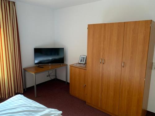 a bedroom with a desk with a television and a wooden cabinet at Pension Hannes in Kirn