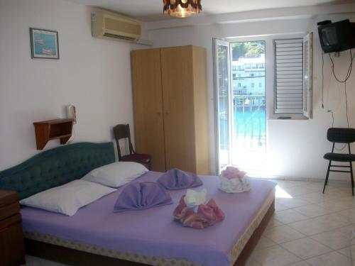 ein Schlafzimmer mit einem Bett mit violetter Bettwäsche und einem Fenster in der Unterkunft Apartments Kaleb - next to the seashore in Stomorska