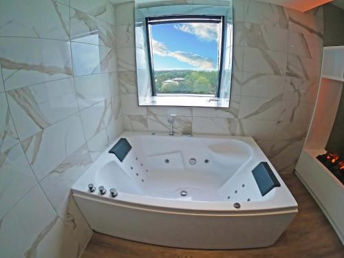 a white bath tub in a bathroom with a window at Riva hotel Den Haag - Delft in The Hague