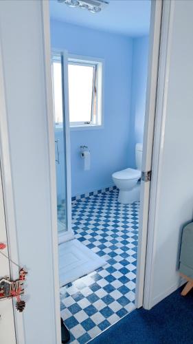 ein blaues Bad mit einem WC und einem Fenster in der Unterkunft Panoramic View Apartment Without a Kitchen in Rotorua