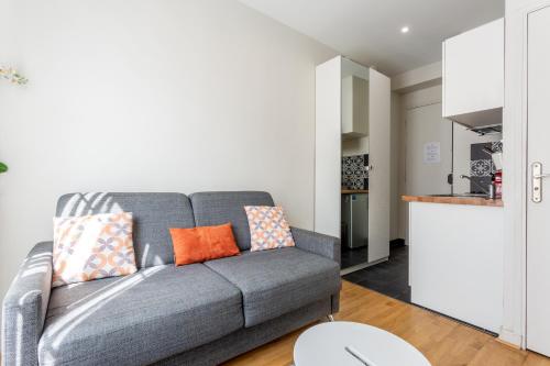 a living room with a gray couch with orange pillows at Studio - Gabriel Peri in Montrouge