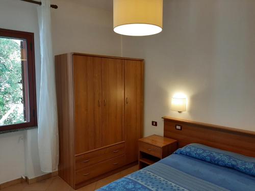 - une chambre avec un lit et une armoire en bois dans l'établissement Villetta sul mare, à Capo Vaticano