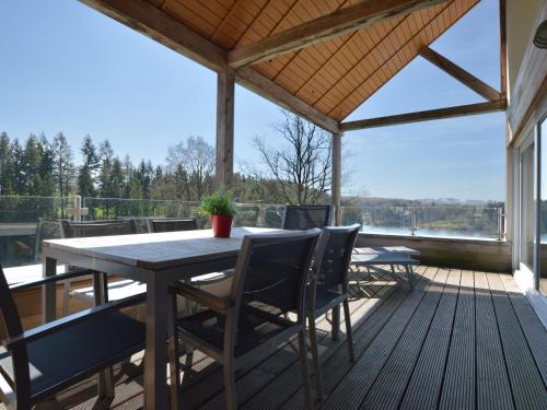 un patio con mesa y sillas en una terraza en Luxury apartment with sauna over a lake, en Robertville