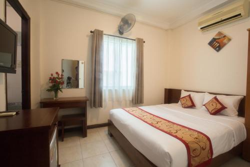 ein Hotelzimmer mit einem Bett, einem Schreibtisch und einem TV in der Unterkunft Ngoc Minh Hotel in Ho-Chi-Minh-Stadt