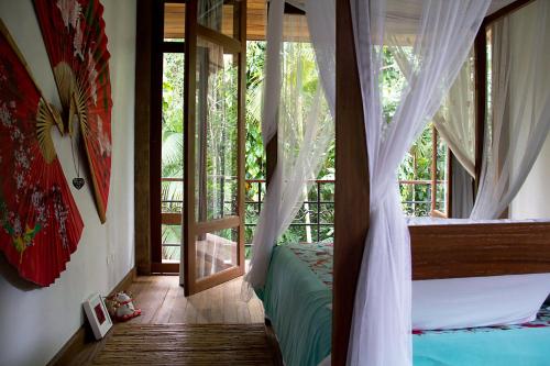 a bedroom with a canopy bed and a balcony at Estalagem Camburi in Camburi