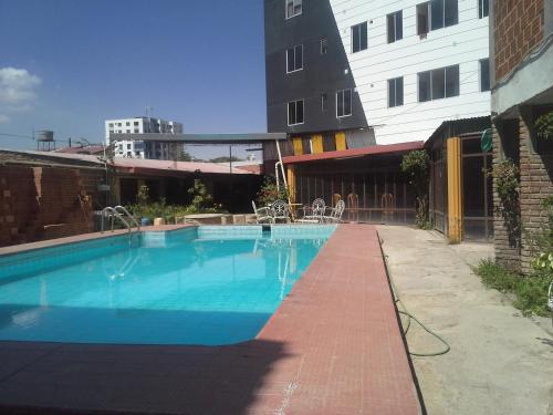 una piscina con una pasarela de ladrillo junto a un edificio en Concordia - Hospedaje, en Cochabamba