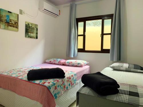 1 dormitorio con 2 camas y ventana en Casa Bombinhas, en Bombinhas