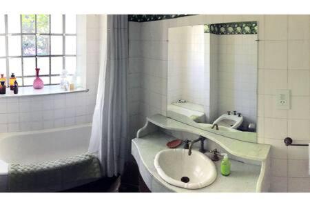 y baño con lavabo, bañera y espejo. en Habitación en casa con gran jardín en San Isidro